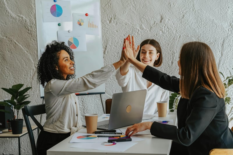 Women in a meeting giving each other a high-five